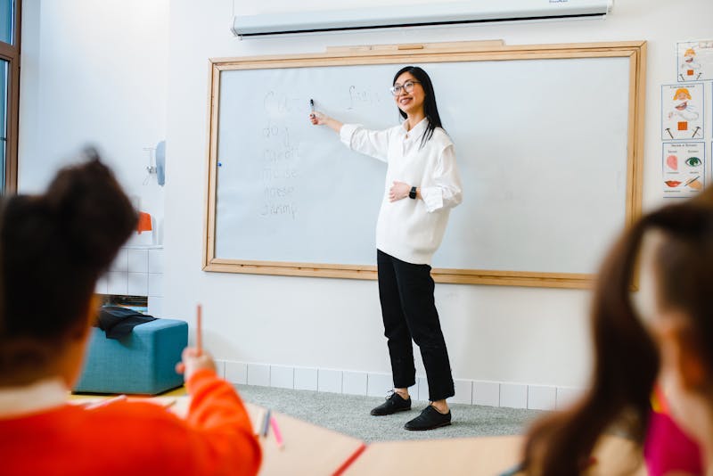 teacher adjusting audio equipment in a classroom with projector screen